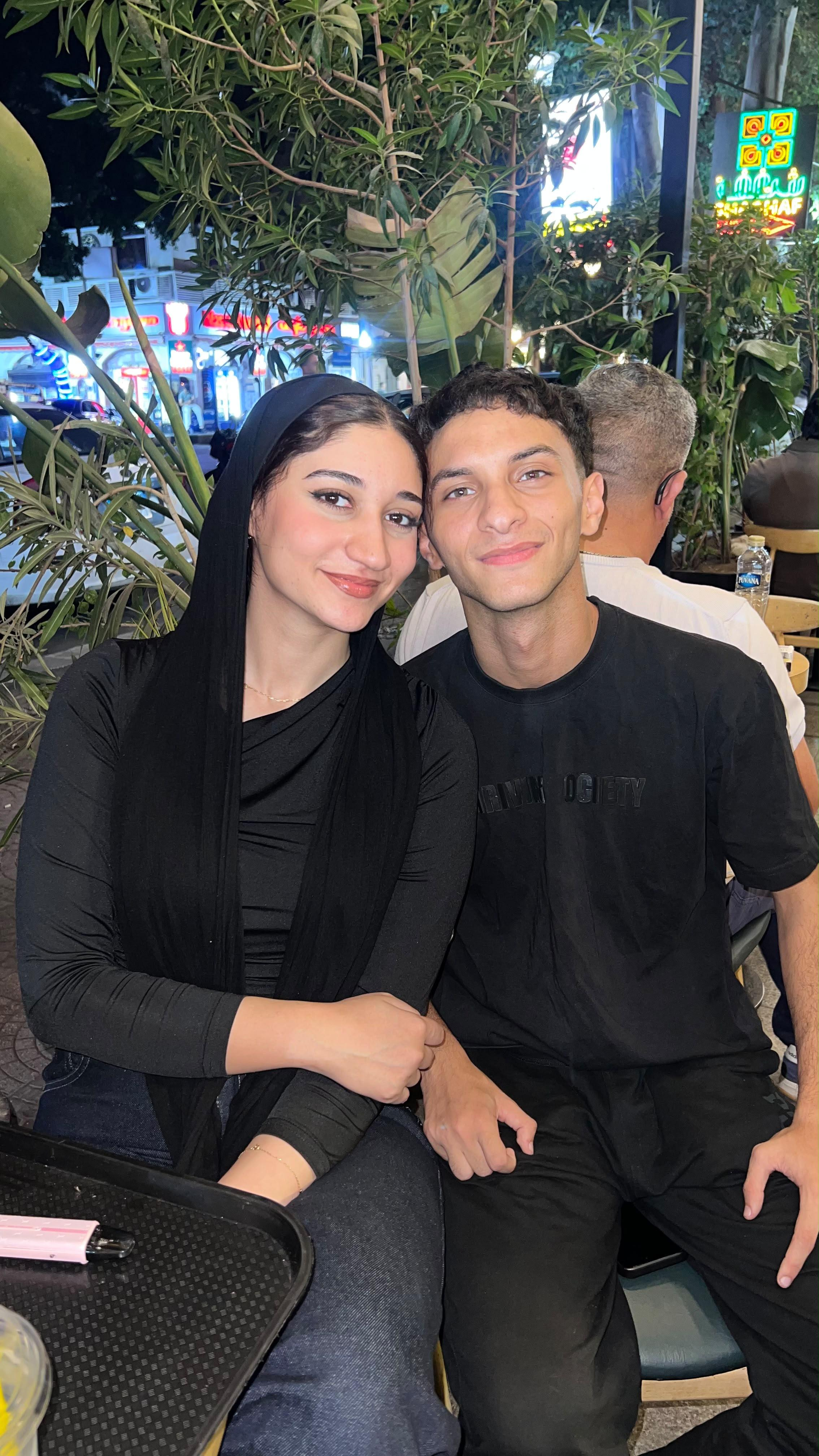 Wed and 3amour sitting side by side with their arms close, smiling at the camera